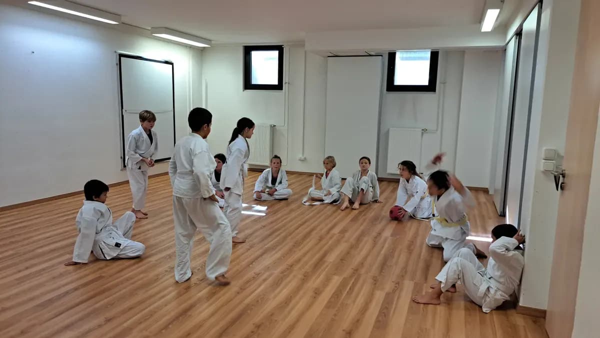 Die Kindergruppe sitzt im Kreis und hört dem Trainer zu